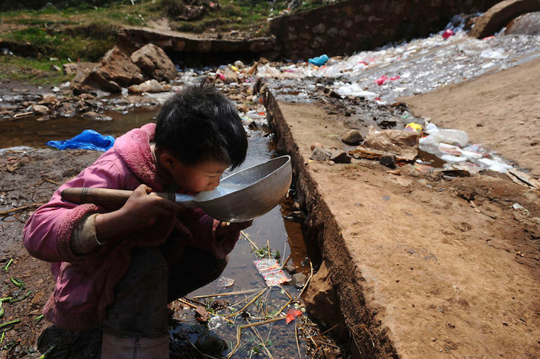 Child drinks water from stream in Fuyuan County, China