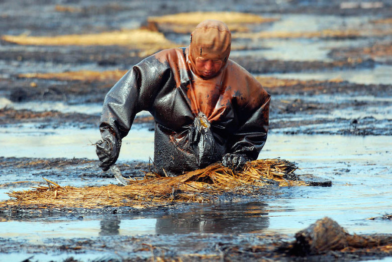 Man cleans up oil spill in Dalian Port, China