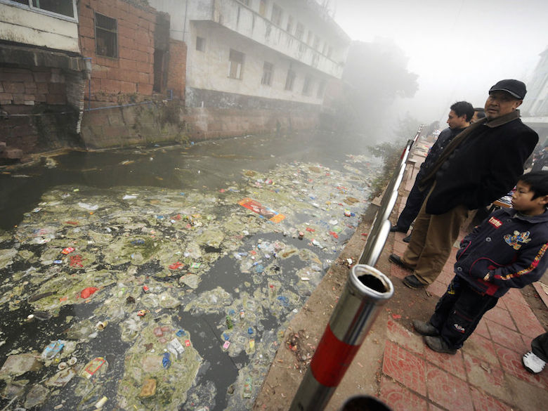 Residents look at a heavily polluted river in Zhugao, China