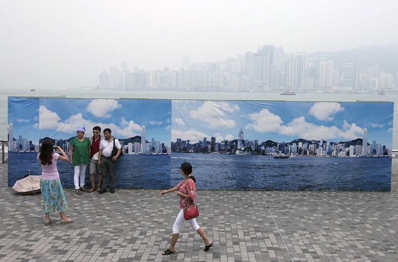 Tourists pose in front of a fake Hong Kong skyline