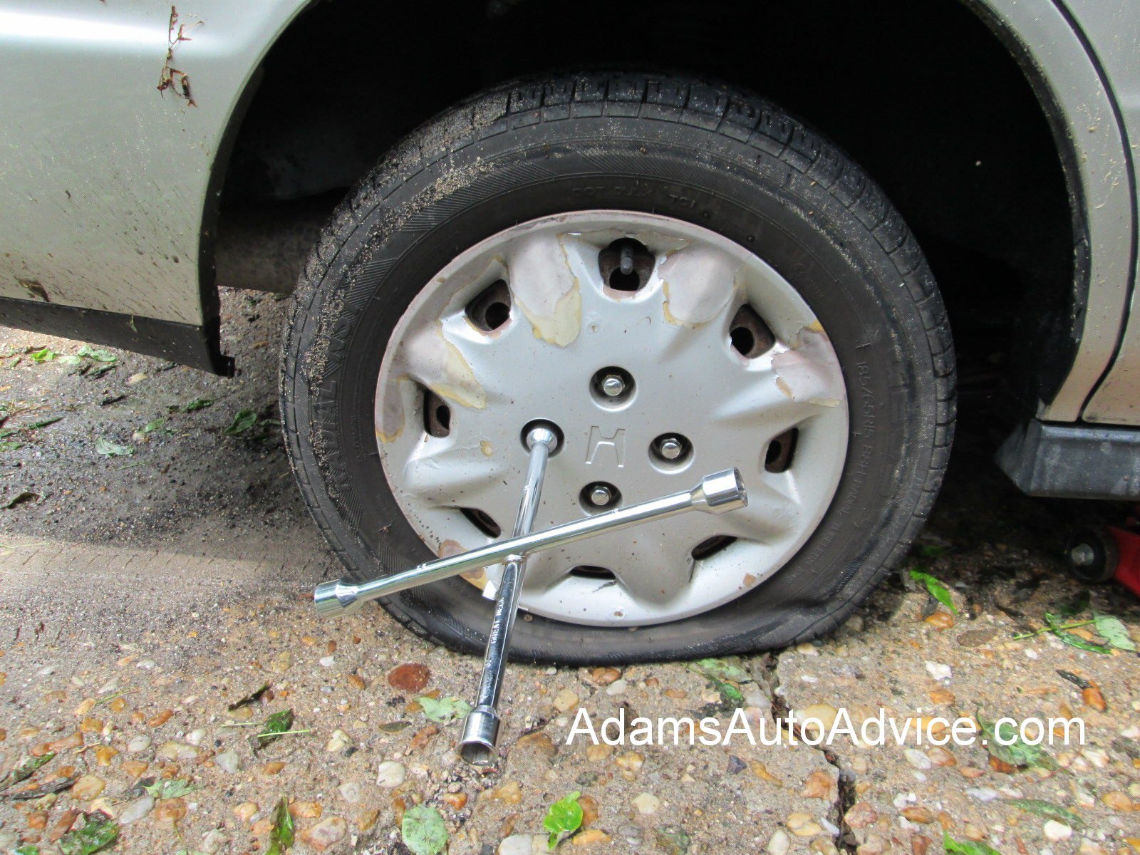 Original Flat Tire Photo Referenced in the Photoshop Joke Photo of a real flat car tire with a lug wrench, used as the original image in a Photoshop prank