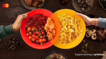 Red and yellow dinner plates overlapping to form the Mastercard logo on a dining table – Mastercard Believe in Experiences campaign by McCann Colombia