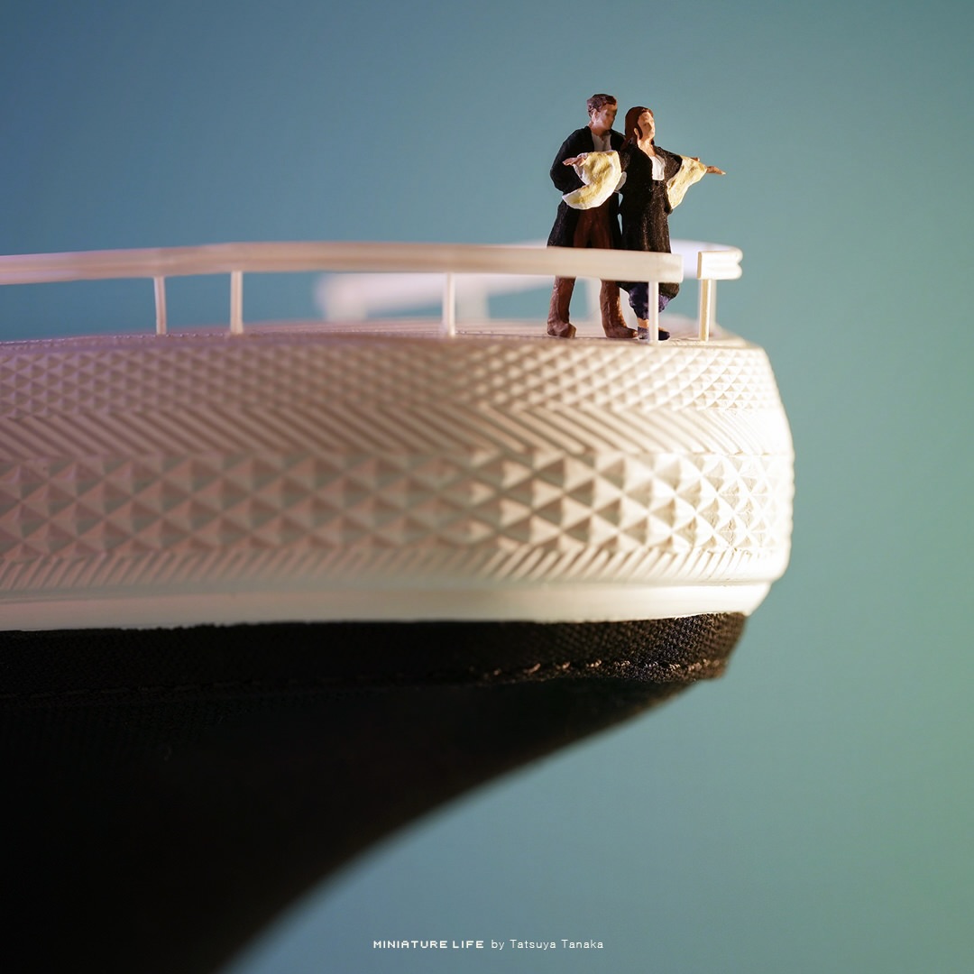 Miniature couple posing at the prow of a slip-on sneaker transformed into a ship deck