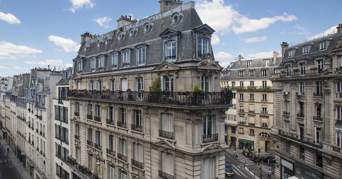 Aerial view of uniform Haussmann-style buildings lining a Paris street with ornate stone facades