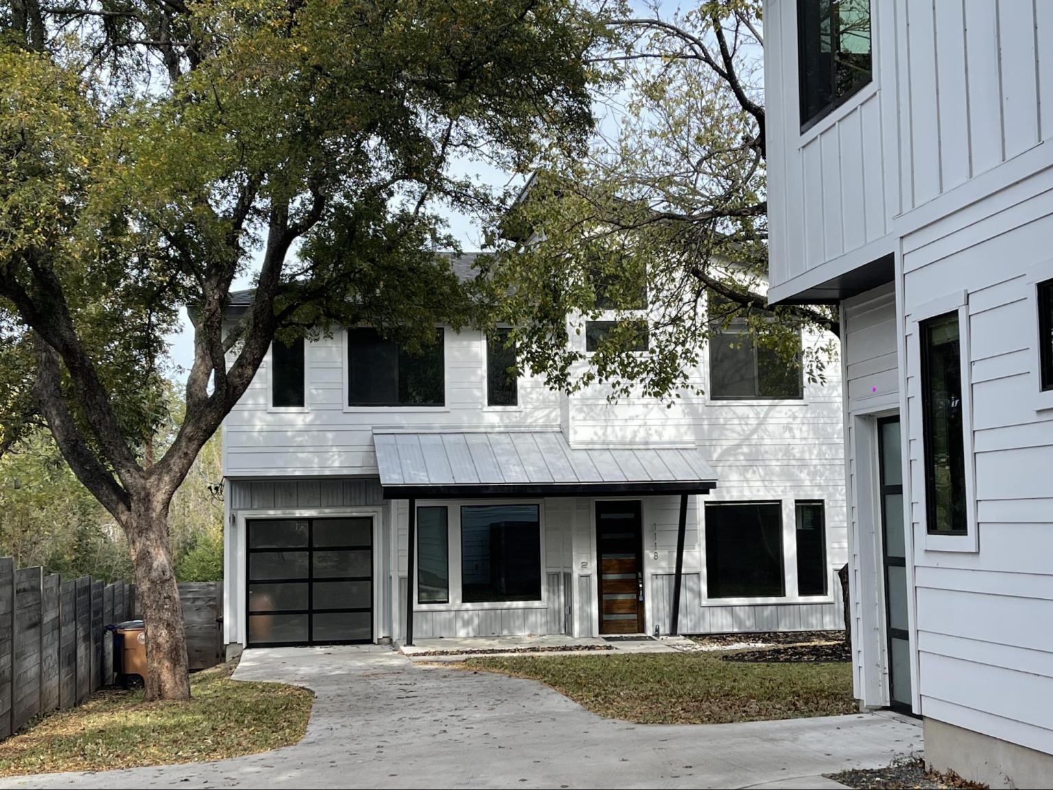 Modern minimalist white house with black window frames and glass garage door in Austin Texas