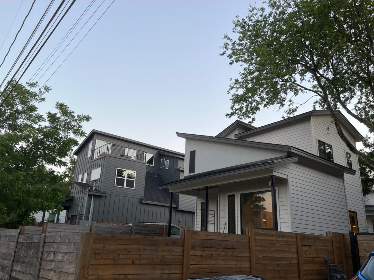 Two identical-looking modern minimalist houses side by side with white and grey siding