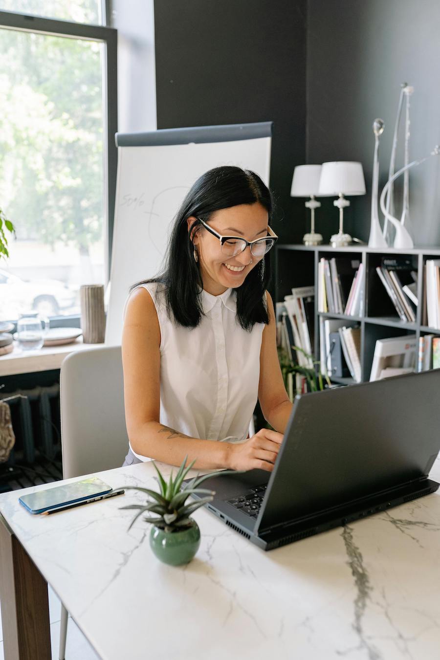 Smiling entrepreneur using a laptop in a modern office setup