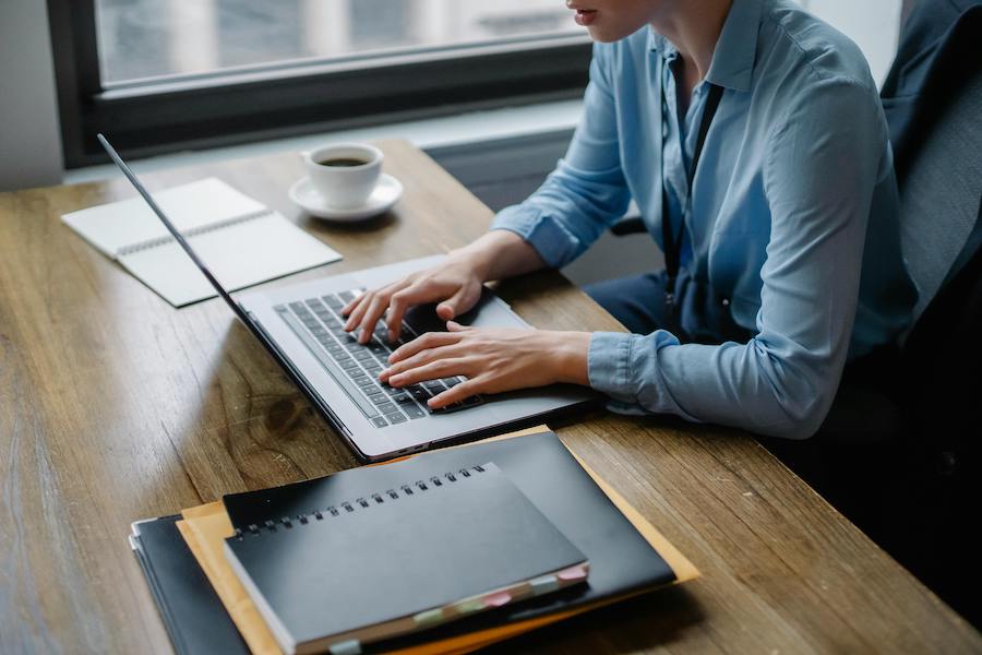 Person building a website on a laptop with a notebook and coffee on the desk