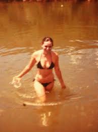 Blurry old photo of a woman in a black bikini walking through a river at age 34