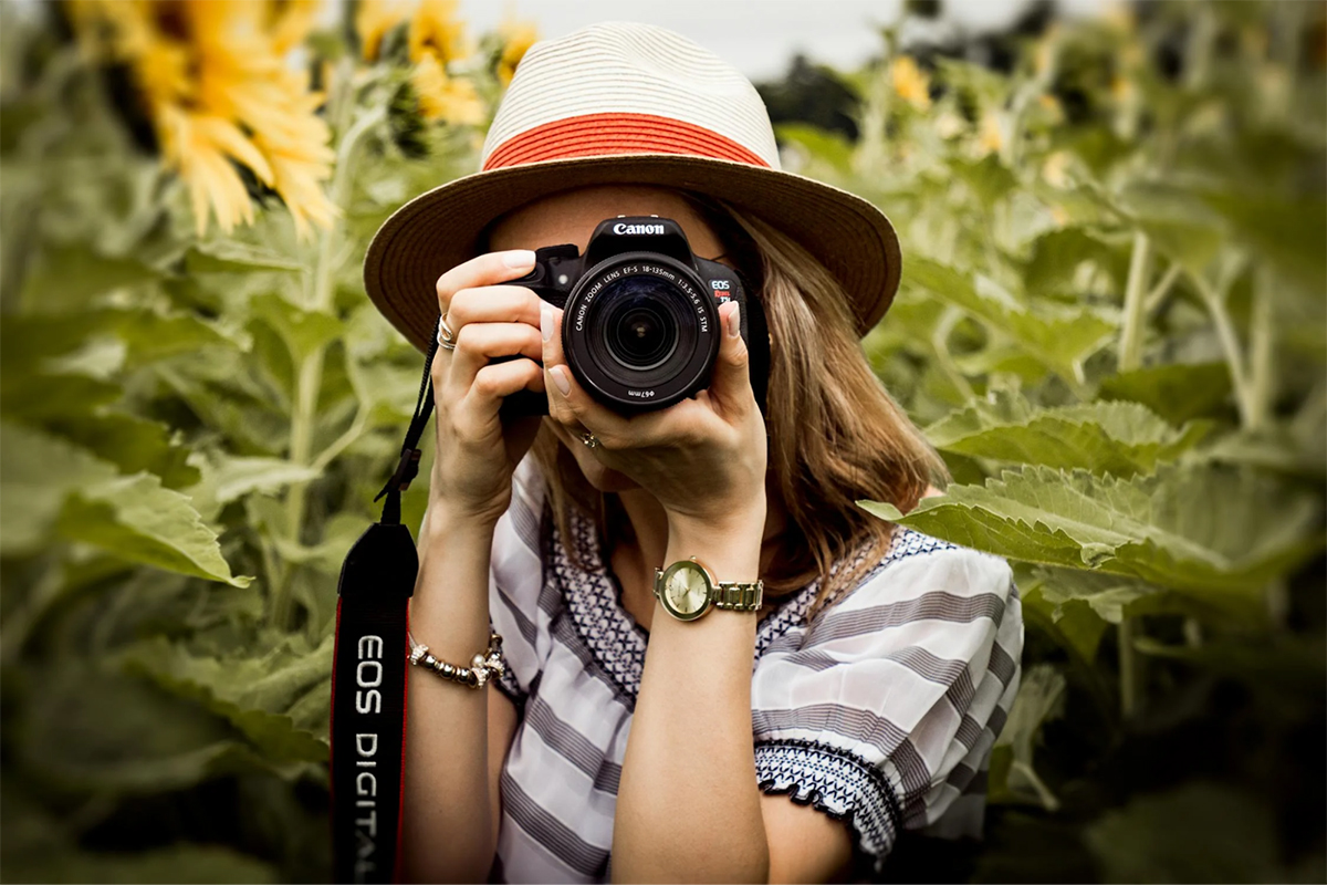 Woman with a DSLR camera taking photos in a sunflower field