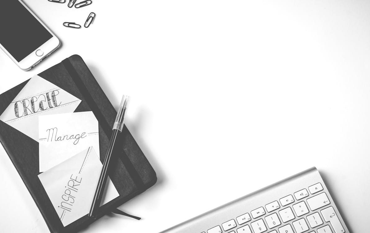 Minimalist workspace with notebook, pen, smartphone, and keyboard