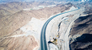 Aerial view of a modern Abu Dhabi highway running through desert mountains