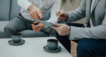 Professionals reviewing client feedback on a tablet during a digital marketing discussion