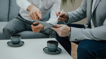 Professionals reviewing client feedback on a tablet during a digital marketing discussion