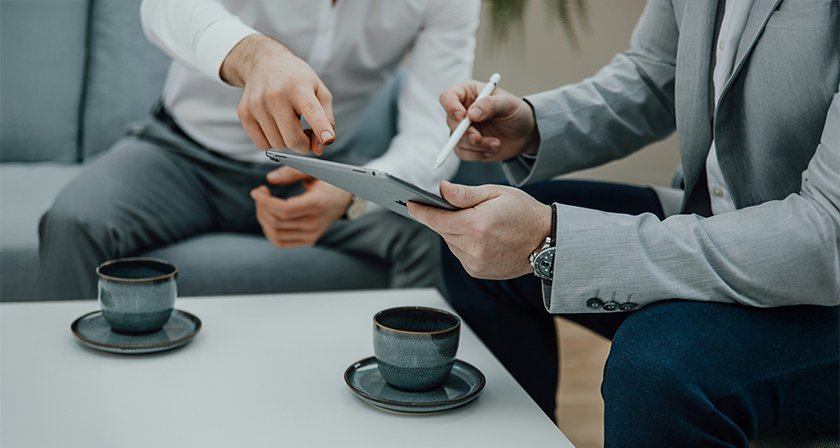 Team members discussing client feedback and marketing strategy on a tablet
