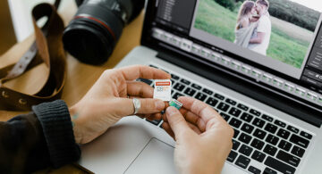 Person holding SD and microSD cards in front of laptop for photo recovery