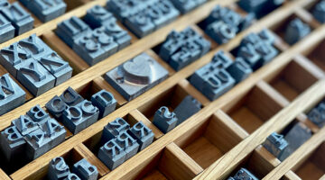 Serif letterpress type blocks in a wooden tray representing traditional typography