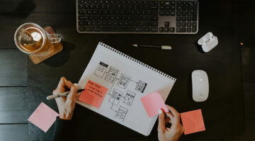 UI/UX designer sketching user flow wireframes in a notebook