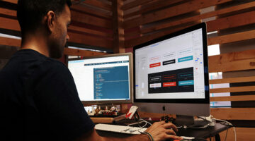 Web designer working on UI layout and code on dual monitors