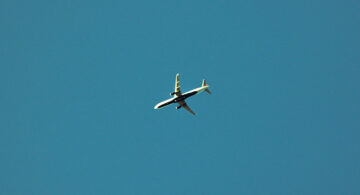 Airplane in clear sky representing travel and remote work for digital creatives