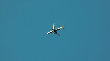 Airplane in clear sky representing travel and remote work for digital creatives