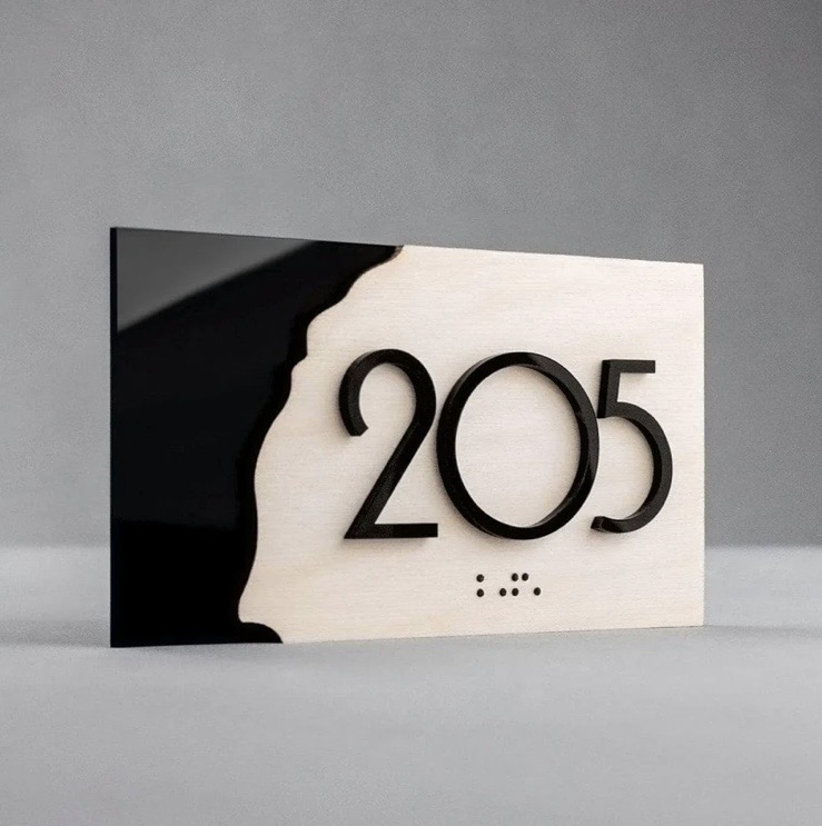 Minimalist wall-mounted room sign with contrasting materials and raised typography