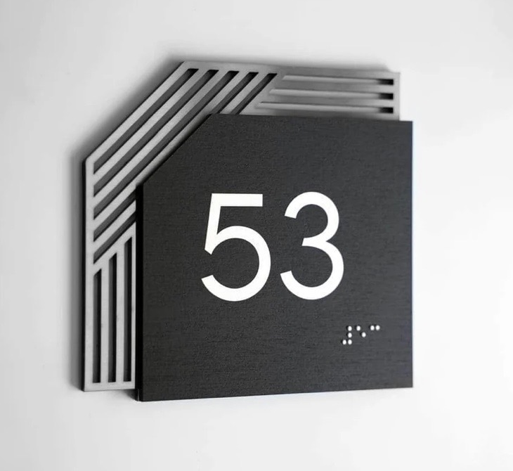 Modern layered room sign with raised numerals and geometric metal backing