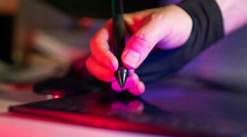 Freelance web designer using a graphics tablet while preparing a client website launch