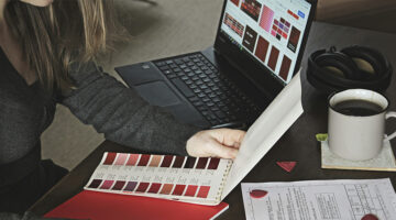 Designer reviewing brand identity colour palettes and website design on a laptop.