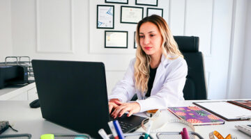 Plastic surgery professional working on a laptop in a modern clinic, highlighting the importance of website design and user experience.