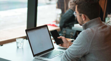 Remote worker using a smartphone and laptop at a café